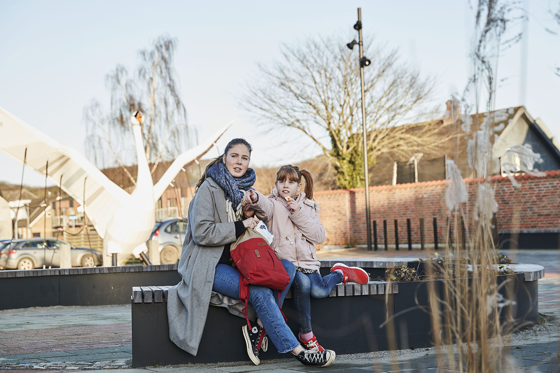 To piger der sidder på en bænk i Auning.