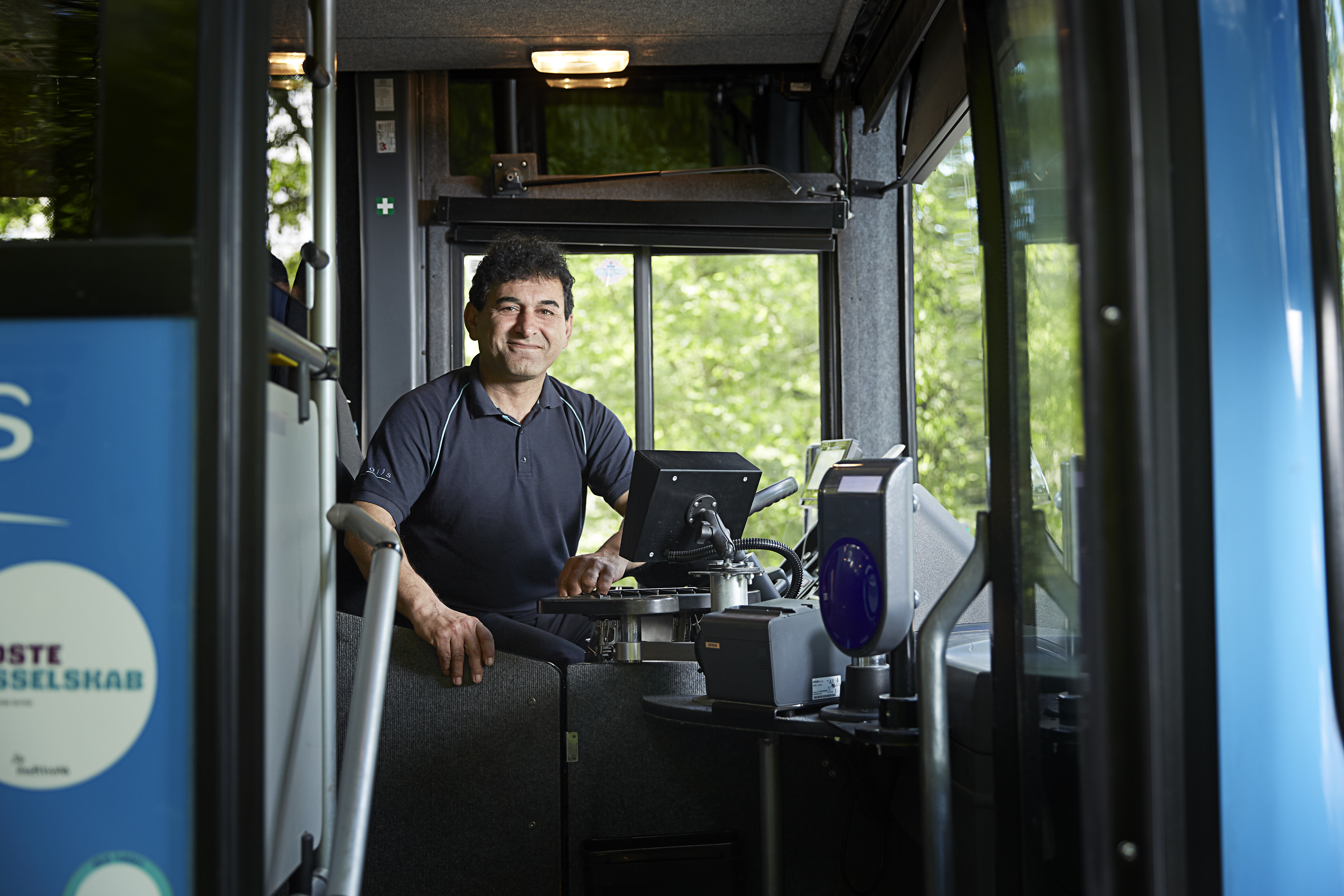 Chauffør, der sidder bag rettet og kigger ud gennem fordøren.